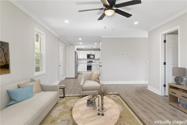 living area featuring baseboards, a ceiling fan, ornamental molding, light wood-style floors, and recessed lighting