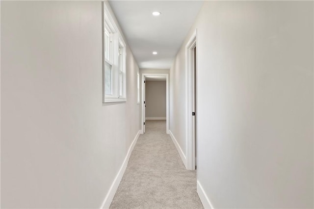 corridor with baseboards, recessed lighting, and light colored carpet