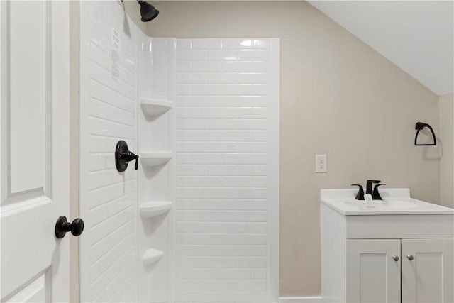 bathroom featuring vaulted ceiling, a shower, and vanity