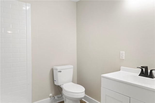 bathroom featuring toilet, baseboards, and vanity