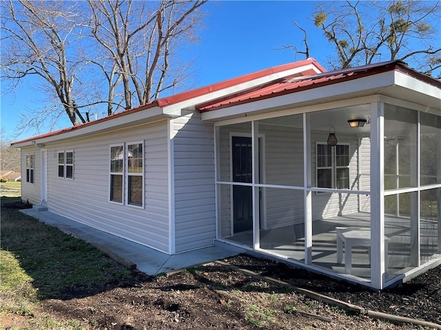 view of side of property featuring a sunroom and metal roof