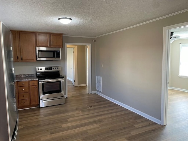 kitchen featuring brown cabinetry, ornamental molding, dark wood-style flooring, stainless steel appliances, and a textured ceiling