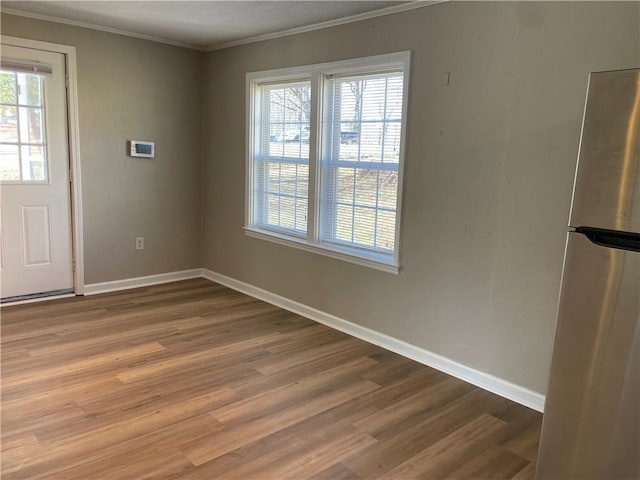 unfurnished dining area with baseboards, a healthy amount of sunlight, wood finished floors, and crown molding