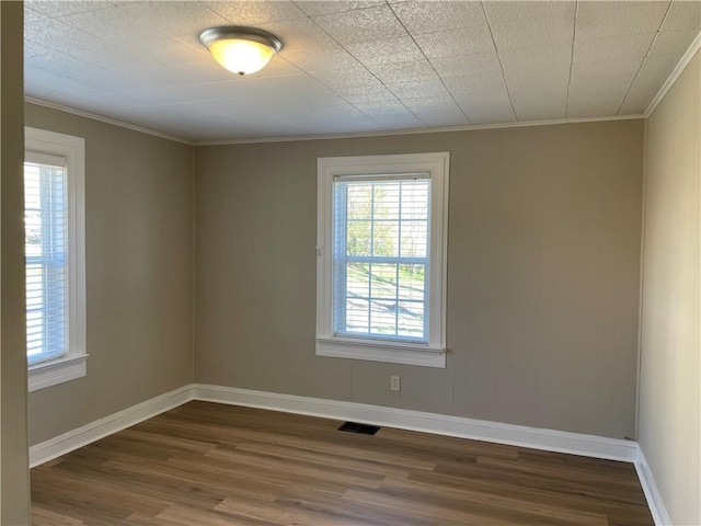 unfurnished room with baseboards, visible vents, dark wood-type flooring, and crown molding