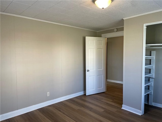 unfurnished bedroom with dark wood-type flooring, crown molding, and baseboards