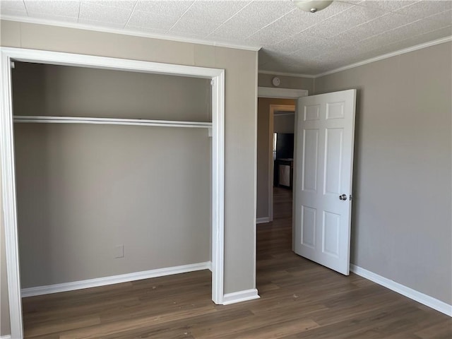 unfurnished bedroom featuring a closet, crown molding, baseboards, and wood finished floors