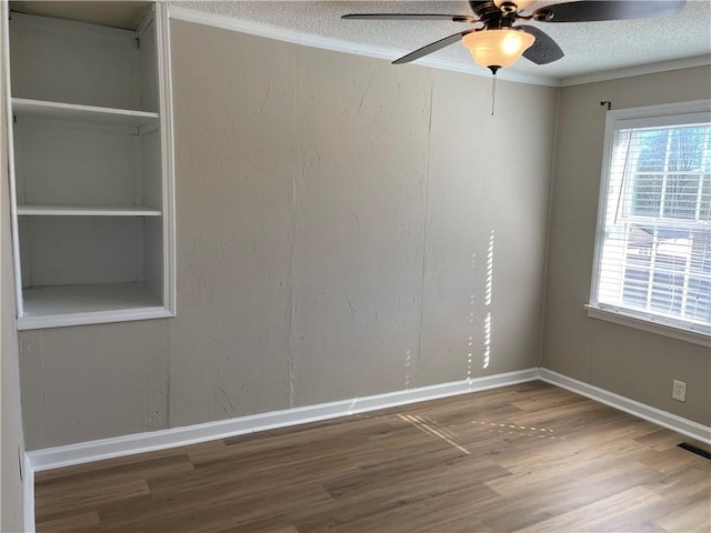 unfurnished room featuring a textured wall, ornamental molding, a textured ceiling, and wood finished floors