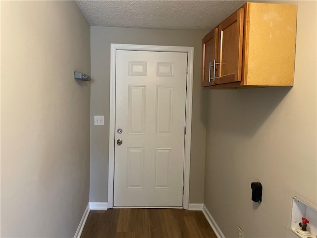 doorway featuring baseboards, dark wood finished floors, and a textured ceiling