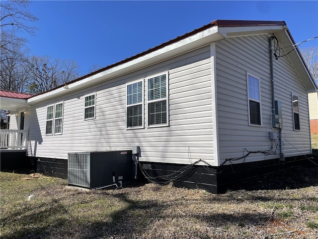 view of side of home with central AC and metal roof