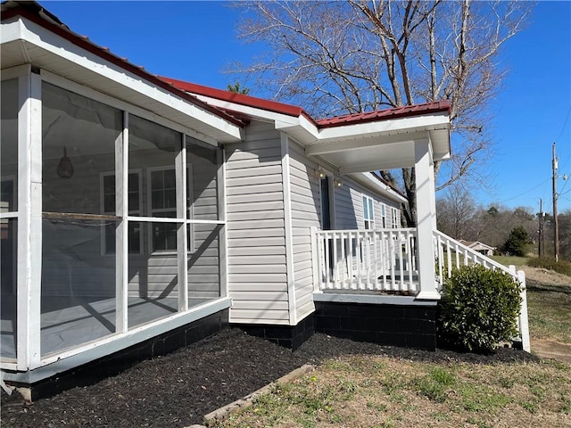 view of home's exterior with metal roof and a sunroom