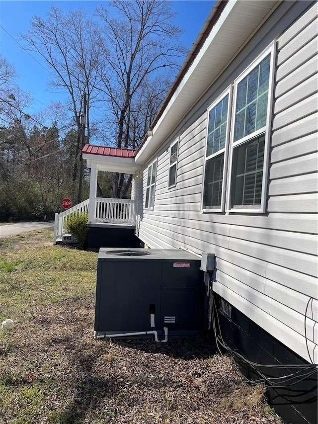 view of side of property with metal roof, crawl space, and central air condition unit