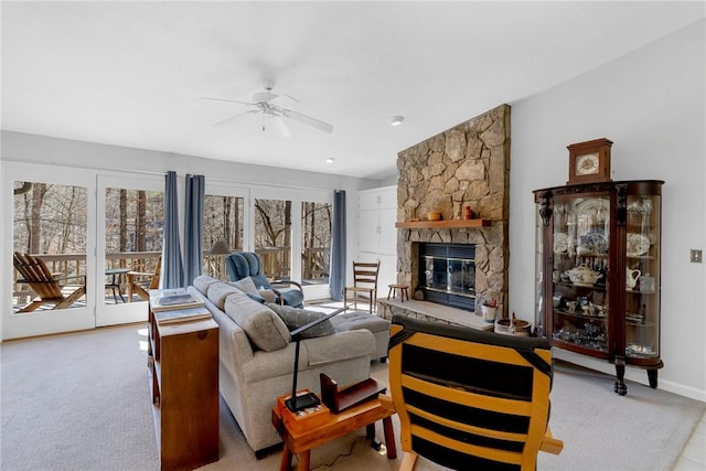 carpeted living room featuring ceiling fan and a stone fireplace