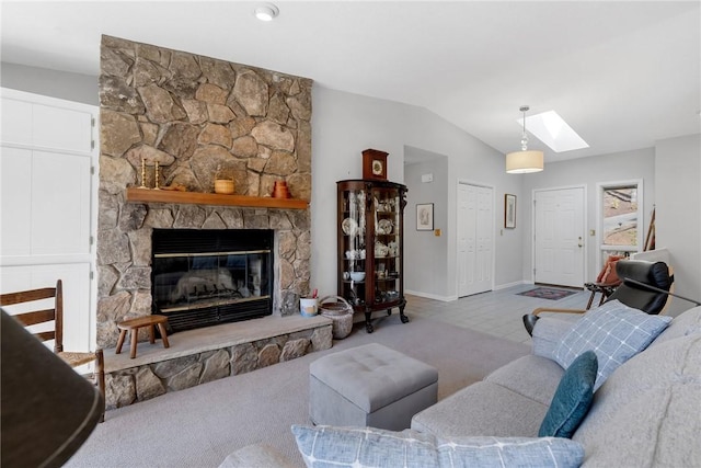 living area with vaulted ceiling with skylight, a stone fireplace, and baseboards