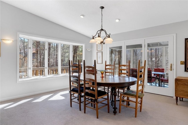 dining space with light carpet, vaulted ceiling, a chandelier, and a healthy amount of sunlight