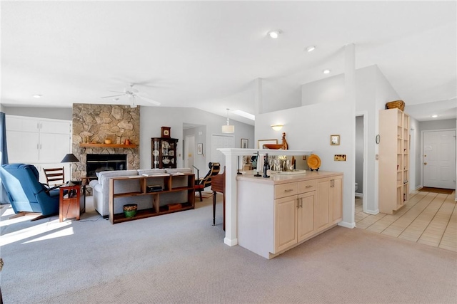 kitchen featuring lofted ceiling, light colored carpet, and a stone fireplace