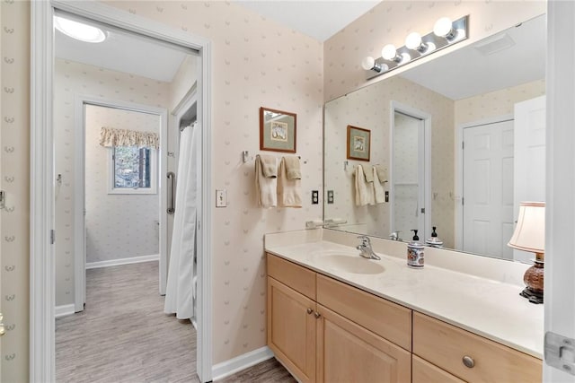 full bathroom with baseboards, wood finished floors, vanity, and wallpapered walls