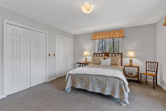 carpeted bedroom featuring baseboards and two closets