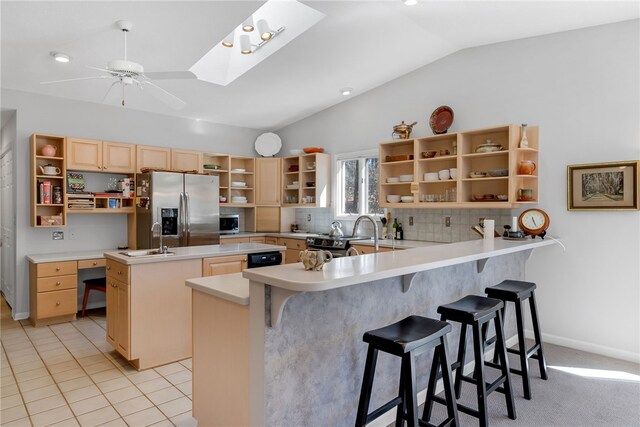 kitchen with lofted ceiling with skylight, a peninsula, stainless steel appliances, open shelves, and a sink