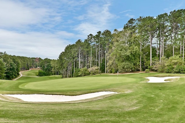 view of property's community featuring view of golf course and a yard