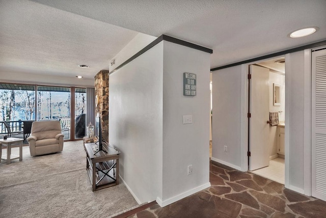 corridor with a textured ceiling, baseboards, and carpet flooring