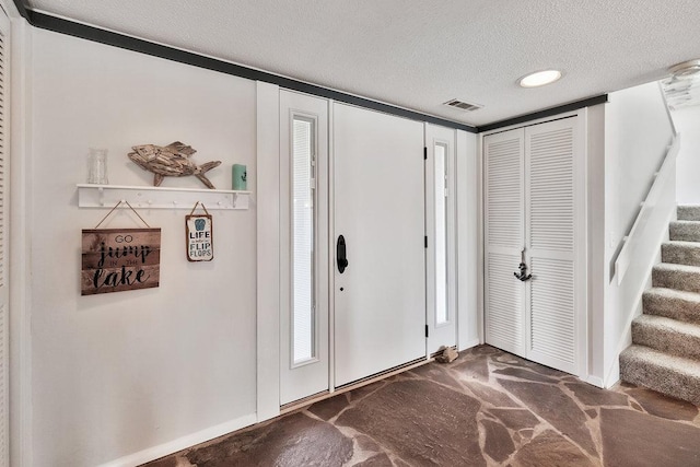 foyer entrance with baseboards, stairs, visible vents, and a textured ceiling