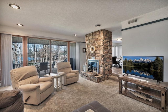 carpeted living room featuring visible vents, a textured ceiling, and a stone fireplace