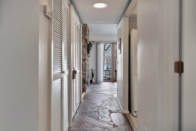 corridor featuring a textured ceiling and stone tile floors