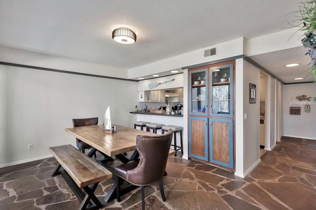 dining room with baseboards, stone floors, visible vents, and a textured ceiling