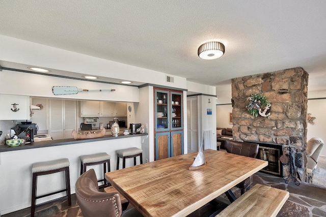 dining area with visible vents, a fireplace, and a textured ceiling