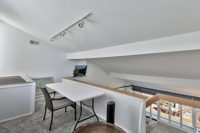 office with a textured ceiling, visible vents, baseboards, vaulted ceiling, and carpet