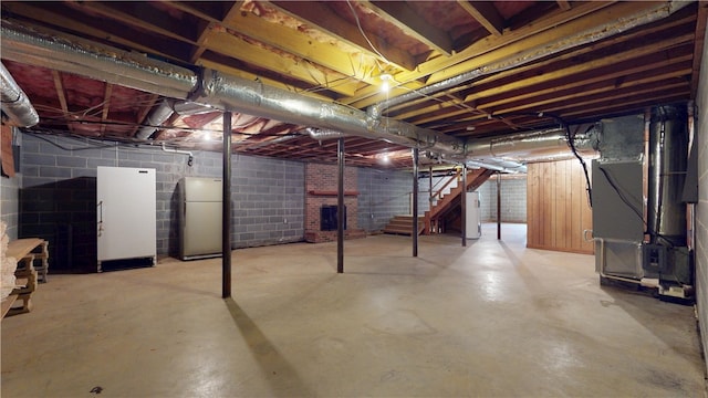 unfinished below grade area with heating unit, stairs, water heater, and freestanding refrigerator