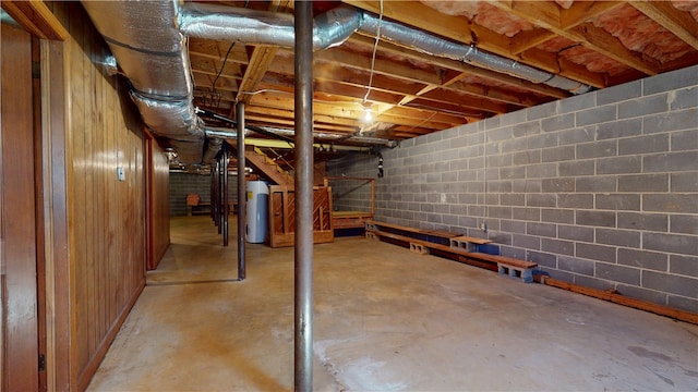 unfinished below grade area featuring concrete block wall and water heater