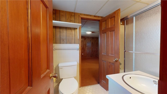 bathroom featuring toilet, wood walls, and a shower with shower door