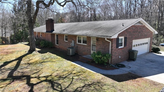 exterior space featuring brick siding, a chimney, a garage, driveway, and a front lawn