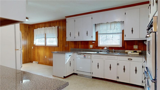 kitchen with light floors, white appliances, a sink, and wooden walls