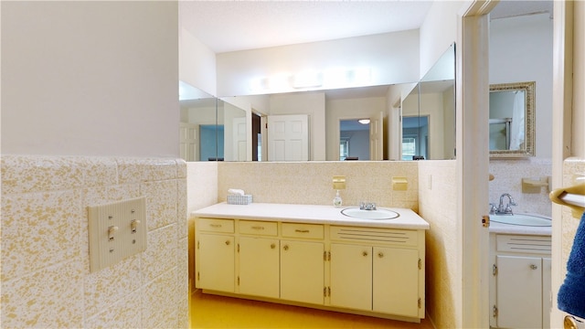 bathroom with two vanities, a sink, and tile walls