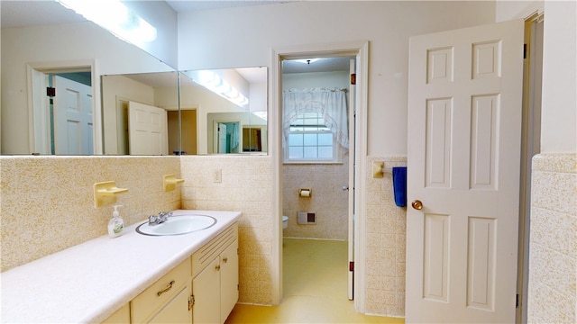 bathroom featuring toilet, a wainscoted wall, tile walls, and vanity