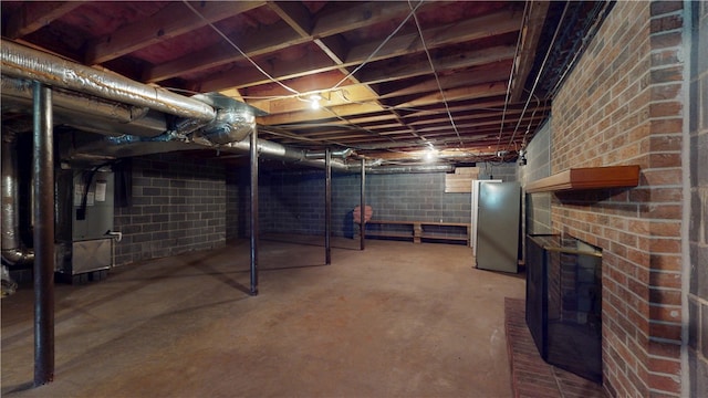 unfinished below grade area with heating unit and freestanding refrigerator