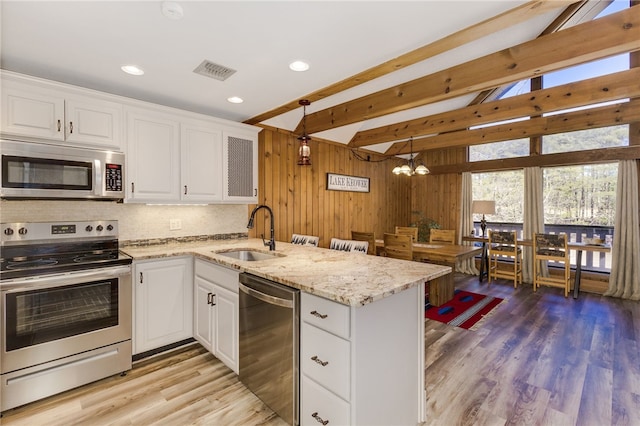 kitchen featuring stainless steel appliances, a peninsula, a sink, visible vents, and white cabinetry