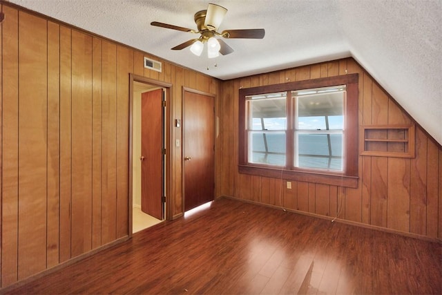 unfurnished bedroom featuring a textured ceiling, wood finished floors, visible vents, and wooden walls