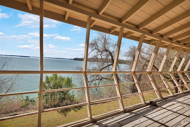 unfurnished sunroom featuring a water view and beamed ceiling