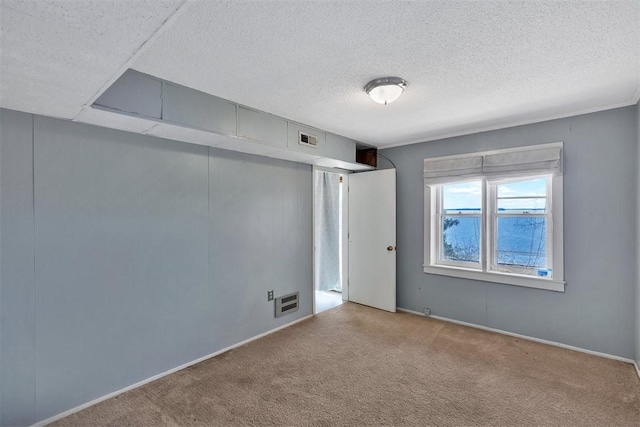 carpeted spare room with a textured ceiling and visible vents