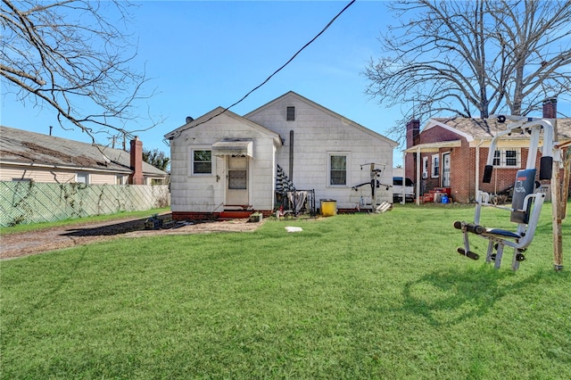 rear view of house featuring entry steps, fence, and a yard