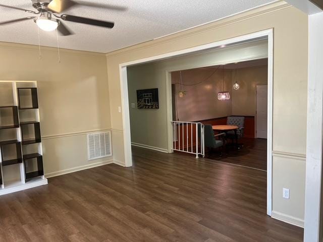 spare room featuring visible vents, ceiling fan, wood finished floors, a textured ceiling, and crown molding