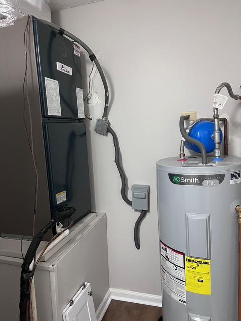 utility room featuring heating unit and water heater