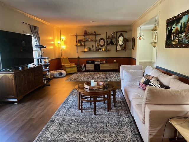 living room featuring wood finished floors and crown molding