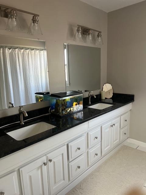 bathroom with double vanity, tile patterned floors, a sink, and baseboards