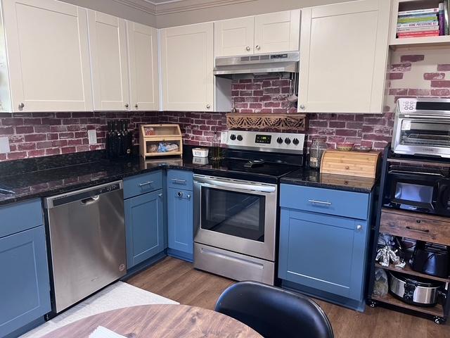 kitchen with blue cabinets, under cabinet range hood, stainless steel appliances, light wood-style floors, and white cabinets