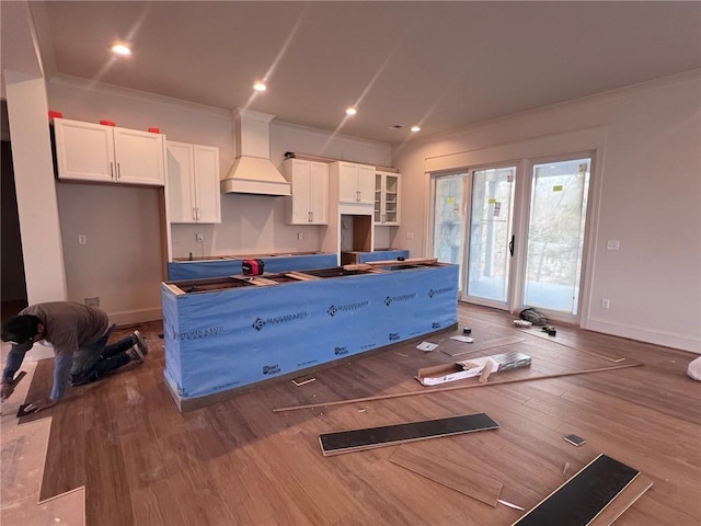 kitchen featuring white cabinetry, crown molding, custom exhaust hood, and wood finished floors