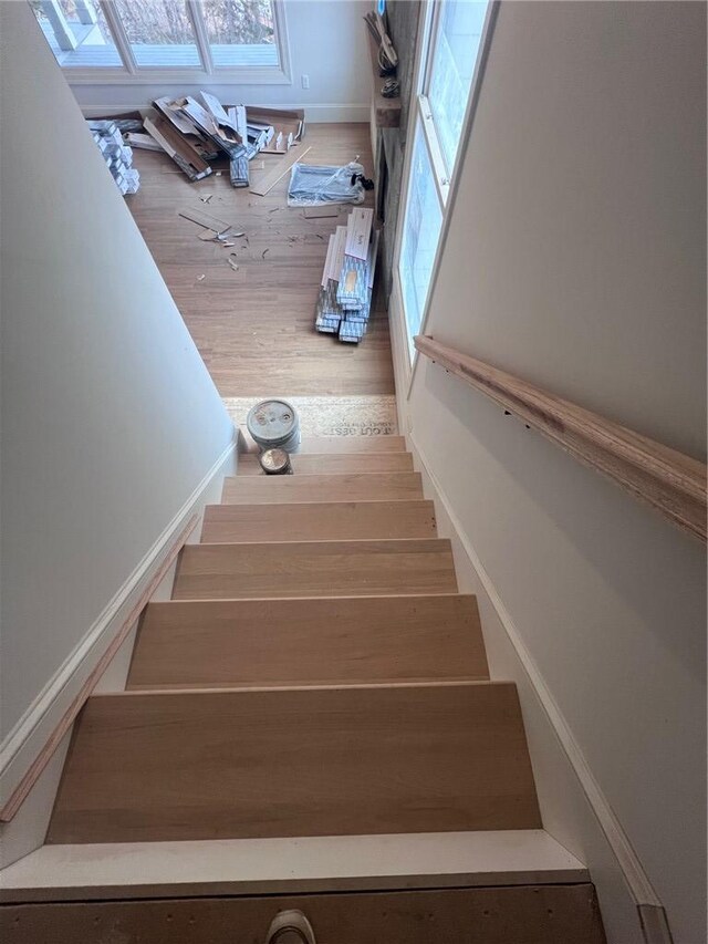 stairway with wood finished floors and baseboards